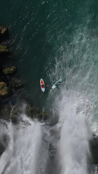 Amazing aerial adventure scenery of people paddling under waterfall