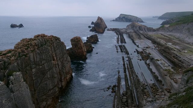 Tripod-mounted cliff-top view across the Urros sea stacks and tilted flysch slabs  Cantabria coast establishing shot