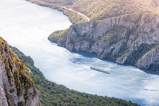 Cruise ship sailing through the deep canyon of the Danube River, a border between Serbia and Romania, a dramatic natural landscape