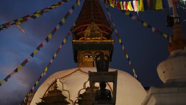 Gilded stupa with watchful Buddha eyes framed by radiating prayer flags at blue hour, Shree Gha Vihar, Kathmandu, Nepal