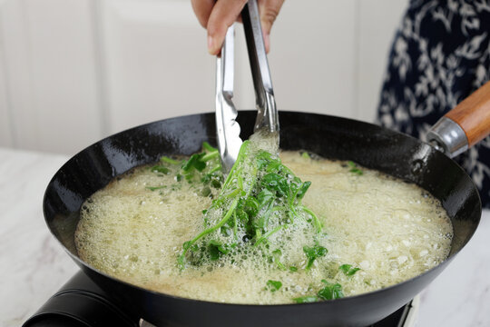 Put Selada Air or Water Cress to Hot Oil on Black Pan