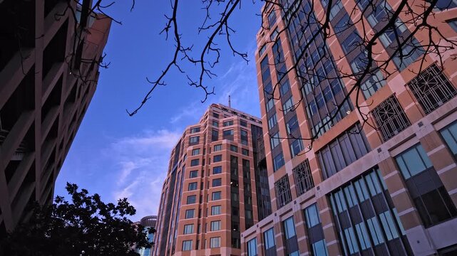 Low-angle perspective of the modern architecture of the Ronald V. Dellums Federal Building in Oakland, California, with a clear blue sky and wispy clouds in the background