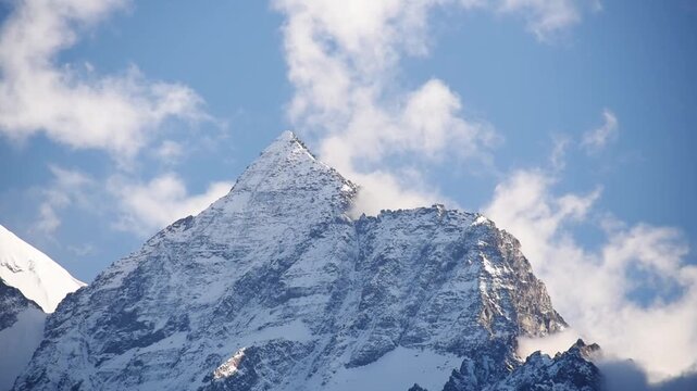 Sharp snow-capped pyramid of the Nilgiri ridge piercing drifting cloud, Upper Mustang, Nepal