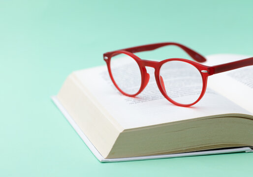 Red Modern Eyeglasses Resting on Open Book
