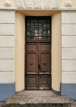 Antique carved wooden door on a classic building facade close up view. Beautiful vintage doorway entryway texture.