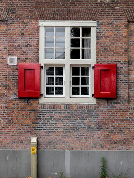 Ventana con postigos rojos en una pared de ladrillo