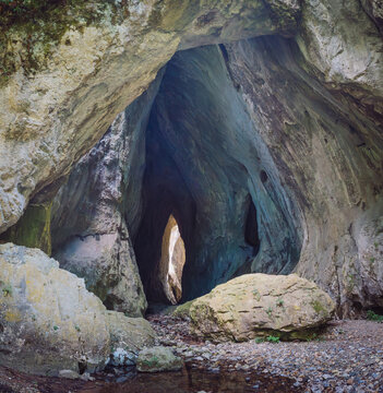 Natural Rajska Prerast cave entrance formed by ancient limestone rock in Serbia, showing geological erosion and pathway to internal darkness