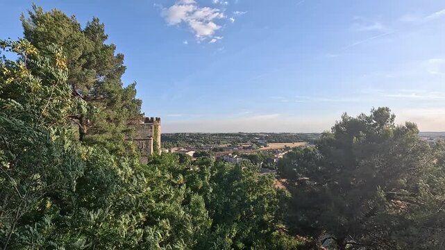 Battlemented cathedral tower above treetops overlooking the Orb plain, Beziers, Herault, Occitanie, France