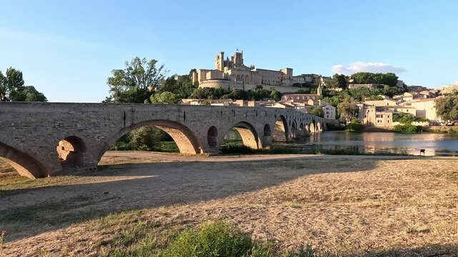 The Pont Vieux over the Orb below Cathedrale Saint-Nazaire at golden hour, Beziers, Herault, France