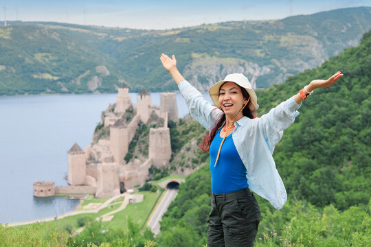 Tourist woman with arms wide open with a medieval riverside fortress Golubac, framing her silhouette from below