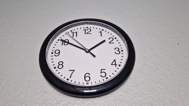 Schlichte schwarze Wanduhr an einer wei&szlig;en Wand &ndash; Thema Zeit und Fristen