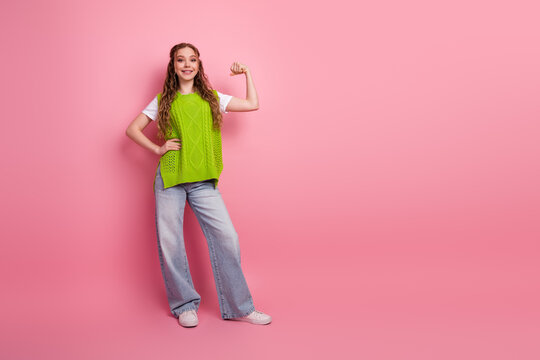 Young girl model in bright green knitted vest posing with confident smile against pink background for fashion lifestyle school style stock photo