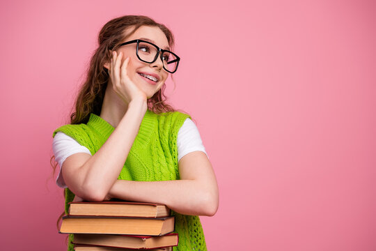 Young girl with glasses holding book smiles against pink background in a bright casual school scene