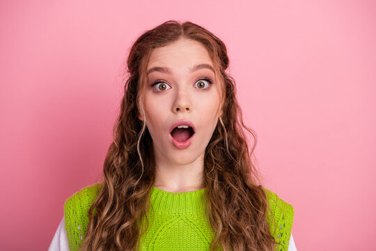 Surprised young woman with pink background wearing lime green sweater smiling widely