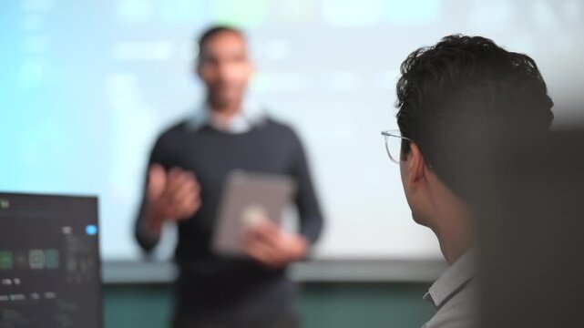 Professional male investors collaborate around a conference table, studying financial graphs and market indicators on a large screen while discussing economic conditions, investment strategies, busine