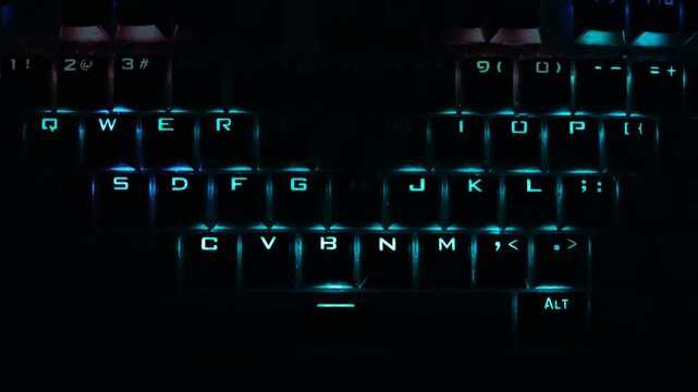 Fast typing motion on a blue lit keyboard in a dark room. Perfect footage for modern technology, hacker aesthetic, cyber security, data analytics, programming, and software engineering clips.