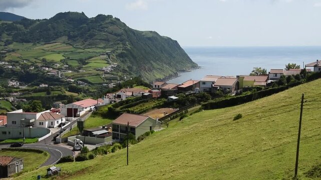  Miradouro da Lomba do Cavaleiro offering view on Povoa&radic;&szlig;&radic;&pound;o a hillside village and pastures running out to a green headland above the sea, Sao Miguel, Azores, Portugal