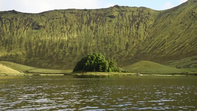 Wooded islet on the Caldeirao lagoon below fluted crater walls, Corvo Island, Western Group, Azores, Portugal