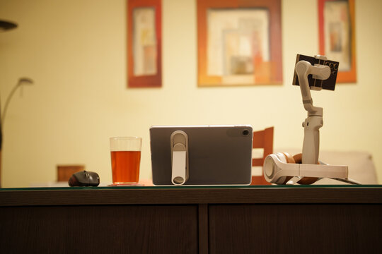 Vintage radio receiver on wooden table beside beer glass and small mouse, with robotic arm in warm indoor scene, framed pictures, soft wall light and cozy retro workspace mood