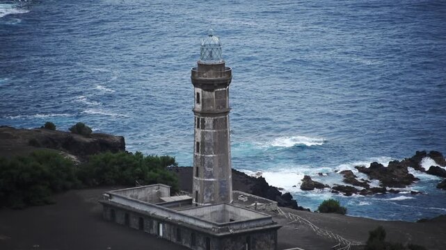 Close up of Capelinhos lighthouse above the lava reef and Atlantic surf on the Capelinhos volcano headland, Faial, Azores