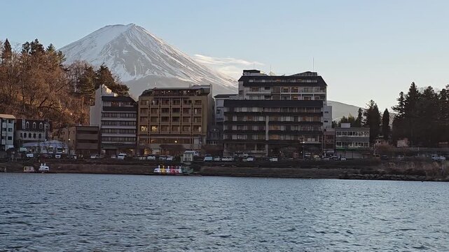 Swan pedalos line the shore of Lake Kawaguchi below Mount Fuji, Fujikawaguchiko, Yamanashi, Japan, at dusk