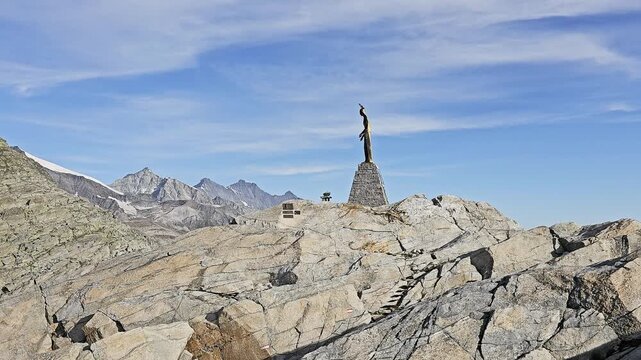 Gilded Madonna delle Nevi above Monte Moro Pass, Valais, Switzerland, standing on its stone plinth against clear blue sky