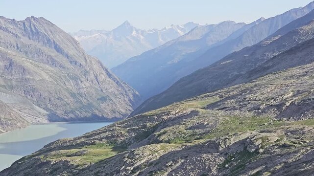 Stausee Mattmark below the Monte Moro Pass, Valais, Switzerland, its pale green water threading a hazy valley at midmorning