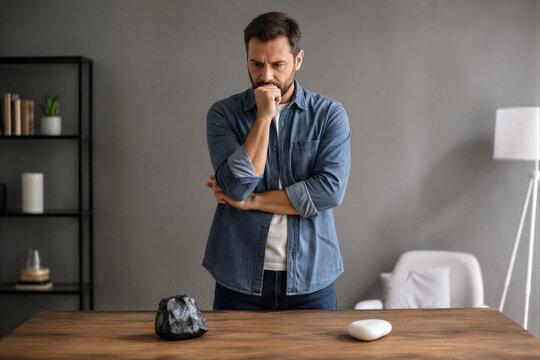 Pensive Man Looking at Two Different Stones Making Difficult Choice
