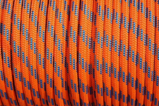 Vue rapproch&eacute;e d'une corde marine orange et bleue enroul&eacute;e offrant un motif r&eacute;p&eacute;titif color&eacute; pr&eacute;sentant des traits courb&eacute;s 