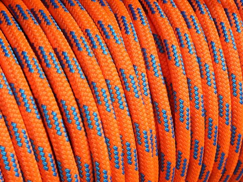 Vue rapproch&eacute;e d'une corde marine orange et bleue enroul&eacute;e offrant un motif r&eacute;p&eacute;titif color&eacute; pr&eacute;sentant des traits courb&eacute;s 