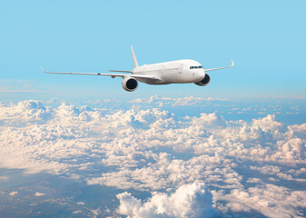 Naklejka premium White passenger airplane flying in the sky amazing clouds in the background - Travel by air transport