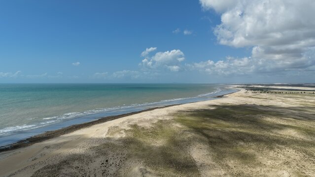 Aerial view of the coastline of Parque Nacional dos Lencois Maranhenses, featuring vast sand dunes and coastal vegetation along the Atlantic Ocean in Atins, Maranhao, Brazil.
