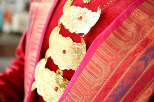 Detail of hands wearing traditional gold jewelry on red ethnic attire