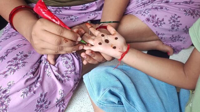 Woman applying traditional henna mehendi design on child palm during festival celebration close up