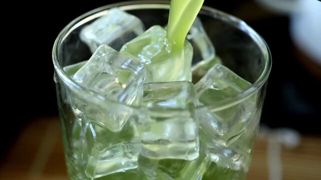 Pouring matcha into a glass with ice