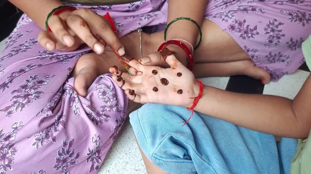 Woman applying traditional henna mehendi design on child palm during festival celebration close up