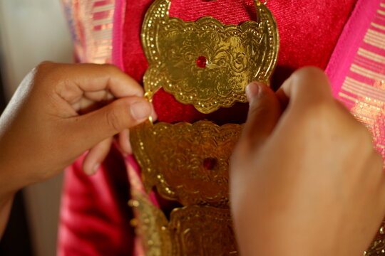 Woman preparing traditional Indonesian dress and golden accessories