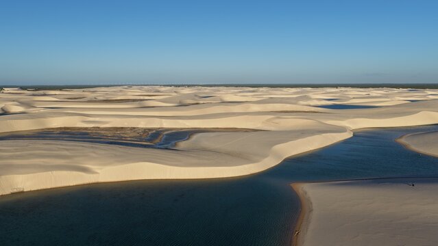 Aerial view of Parque Nacional dos Lencois Maranhenses with vast white sand dunes and crystal clear rainwater lagoons under a clear blue sky Atins, Maranhao, Brazil.