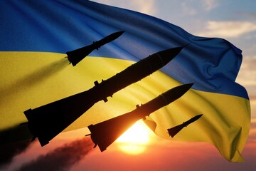 Obraz premium Missile silhouettes fly past the Ukrainian flag at sunset. Armed conflict and defense concepts are visually represented with weapons and national symbols against a dramatic sky.
