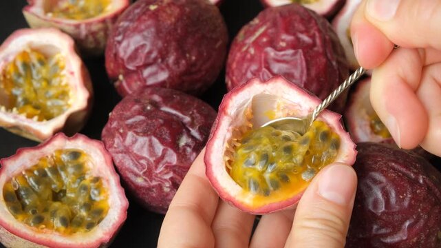 Close up of spoon scooping juicy pulp out of passion fruit shell