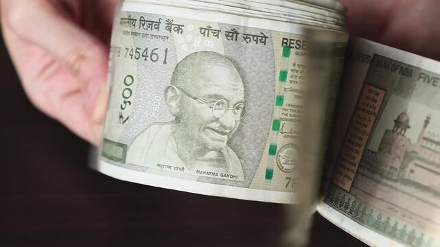 Female Hands Counting 500 Indian Rupee Banknotes in Close-Up. Cash Handling and Personal Finance Concept. Fingers fan through a stack of currency bills