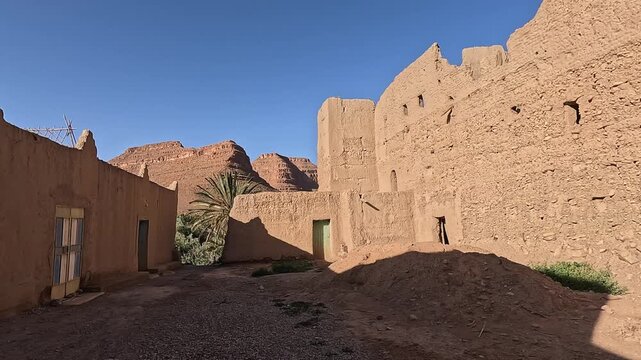 Earthen kasbah ruins and palm below cliffs in the Ziz Canyon, Draa-Tafilalet, Morocco