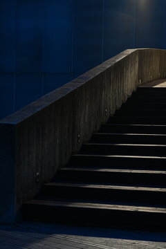 Modern concrete staircase illuminated by dramatic light in night dark blue architectural setting