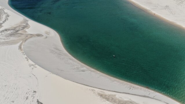 Aerial view of the turquoise lagoon surrounded by white sand dunes in Parque Nacional dos Lencois Maranhenses, Atins, Maranhao, Brazil.