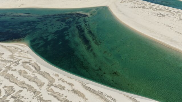 Aerial view of Parque Nacional dos Lencois Maranhenses featuring turquoise lagoons nestled between vast white sand dunes under clear skies Atins, Maranhao, Brazil.