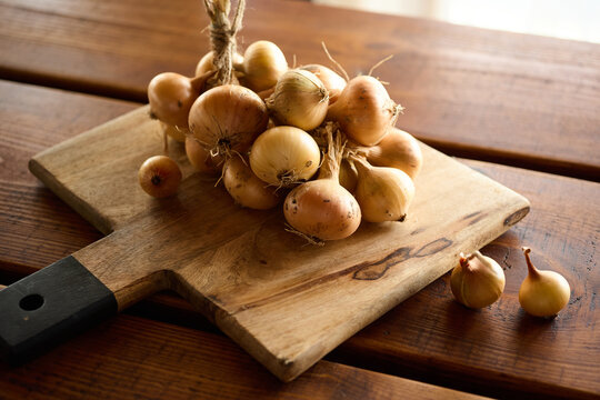 Onion bunch on a wooden cutting board in a kitchen setting