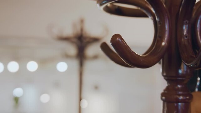 Close up of wooden coat rack with metal hooks in soft focus. hand places and removes hangers emphasizing interaction between human activity and clothing storage objects. background features
