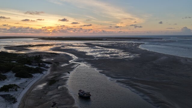 Aerial view of a small boat moored in the river estuary at sunset near Parque Nacional dos Lencois Maranhenses in Atins, Maranhao, Brazil.