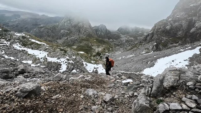 Solo male hiker on a dangerous mountain trail, climbing down a large rock field in the mountains of Montenegro