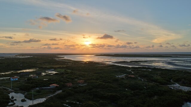 Aerial view of the sunset over the lush vegetation, winding waterways, and small houses of Atins near Parque Nacional dos Lencois Maranhenses in Atins, Maranhao, Brazil.